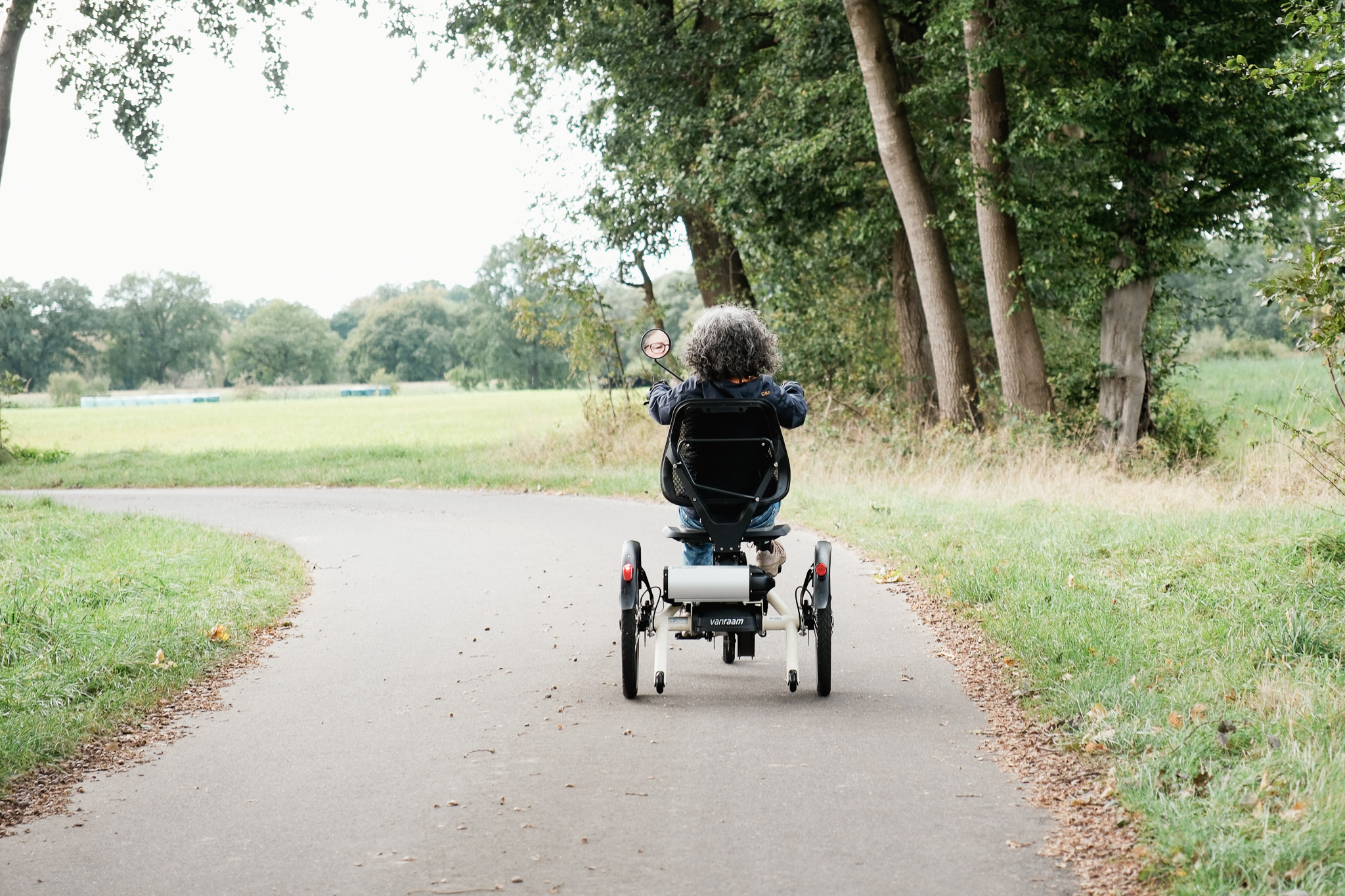 Frau fährt auf einem Dreirad auf einem Fahrradweg