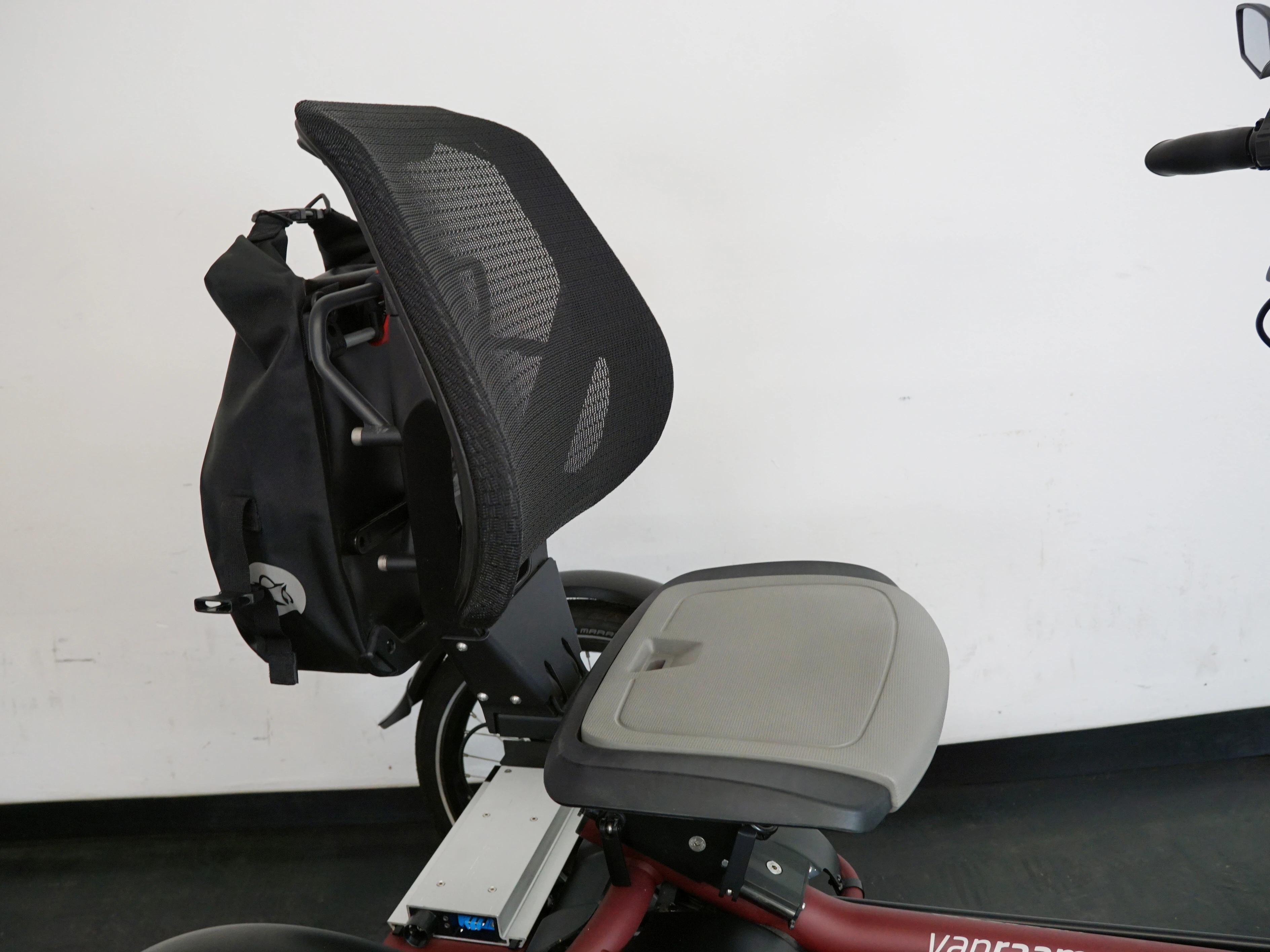 großer Sitz mit Rückenlehne und dahinter eine Tasche