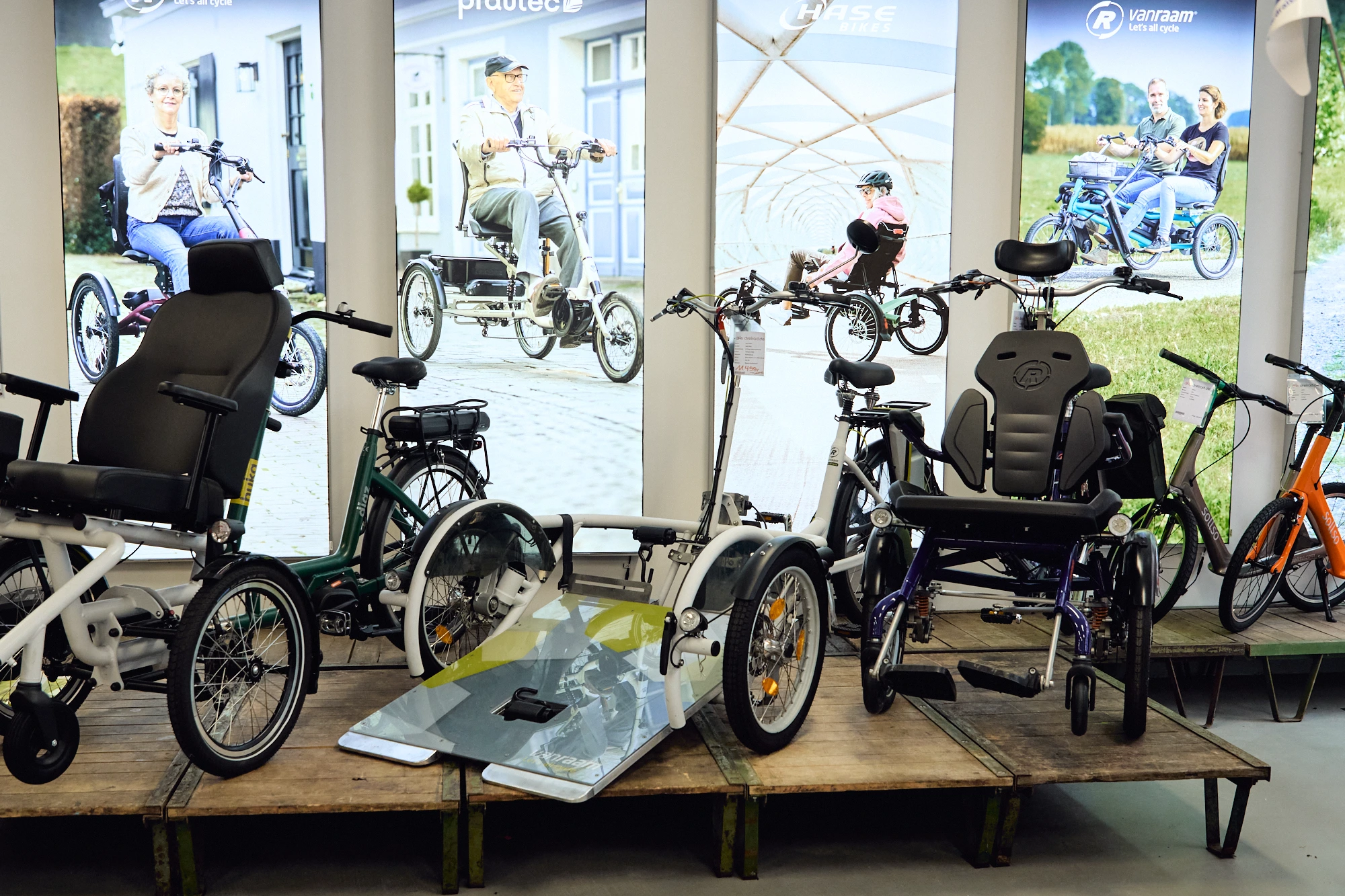 verschiedene Rollstuhlfahrräder stehen auf einem Podest im Laden