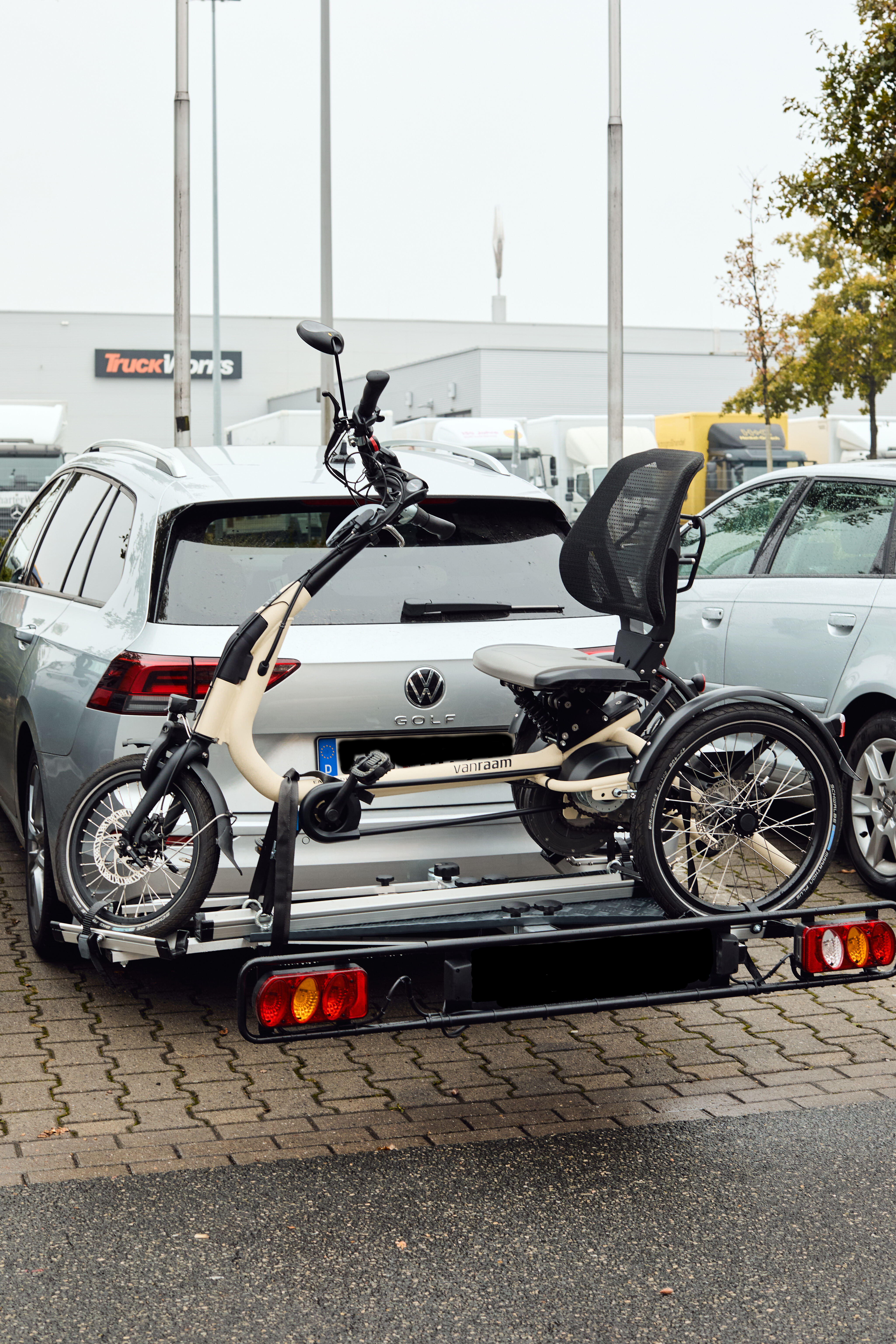 E-Dreirad steht sicher befestigt auf einem Fahrradträger am geparkten Auto.