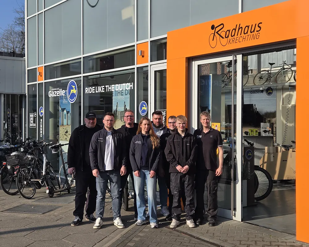 Mitarbeiter:innen stehen vor ihrem Fahrradladen und lächeln