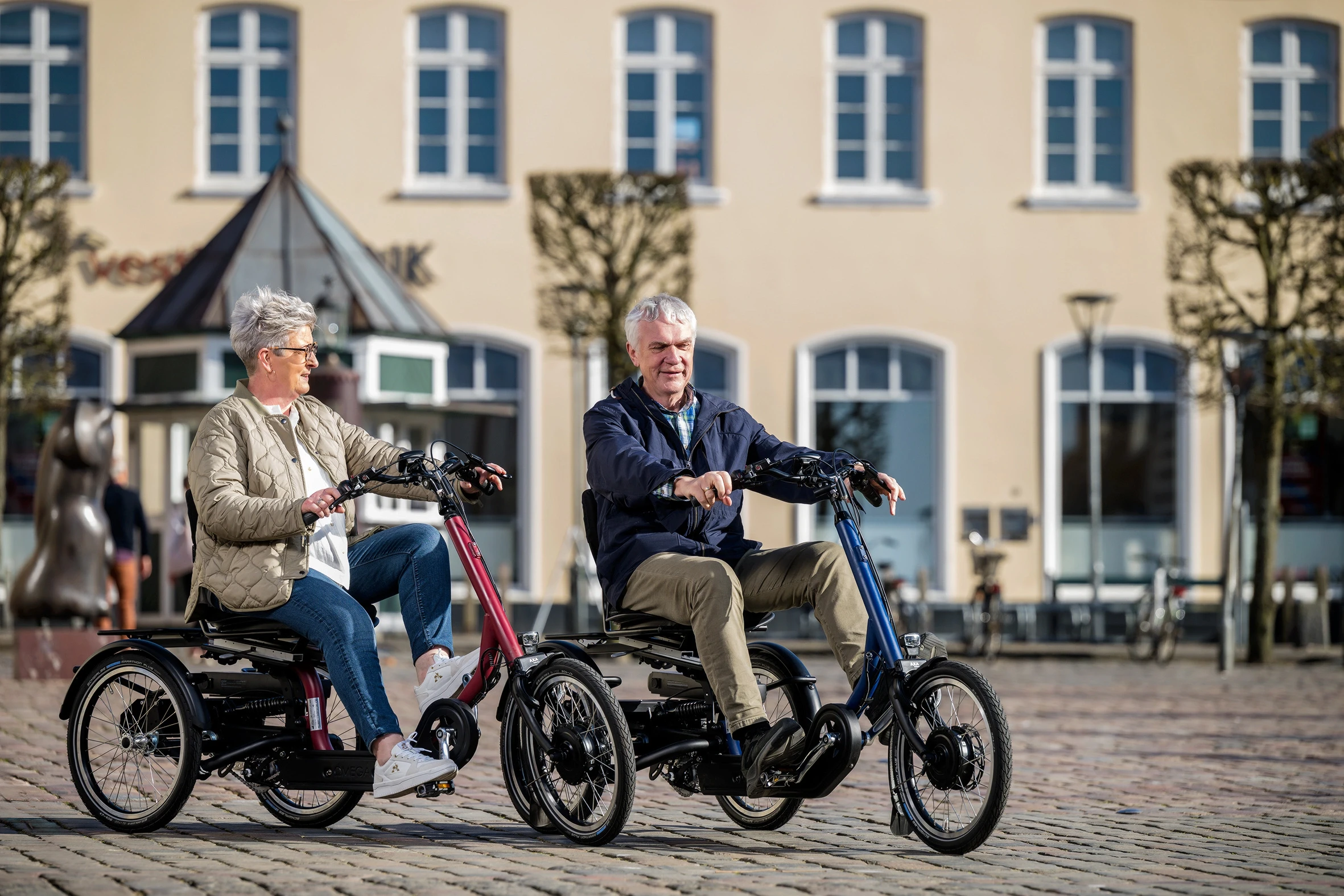 Eine Frau und ein Mann fahren jeweils mit einem Dreirad in der Stadt