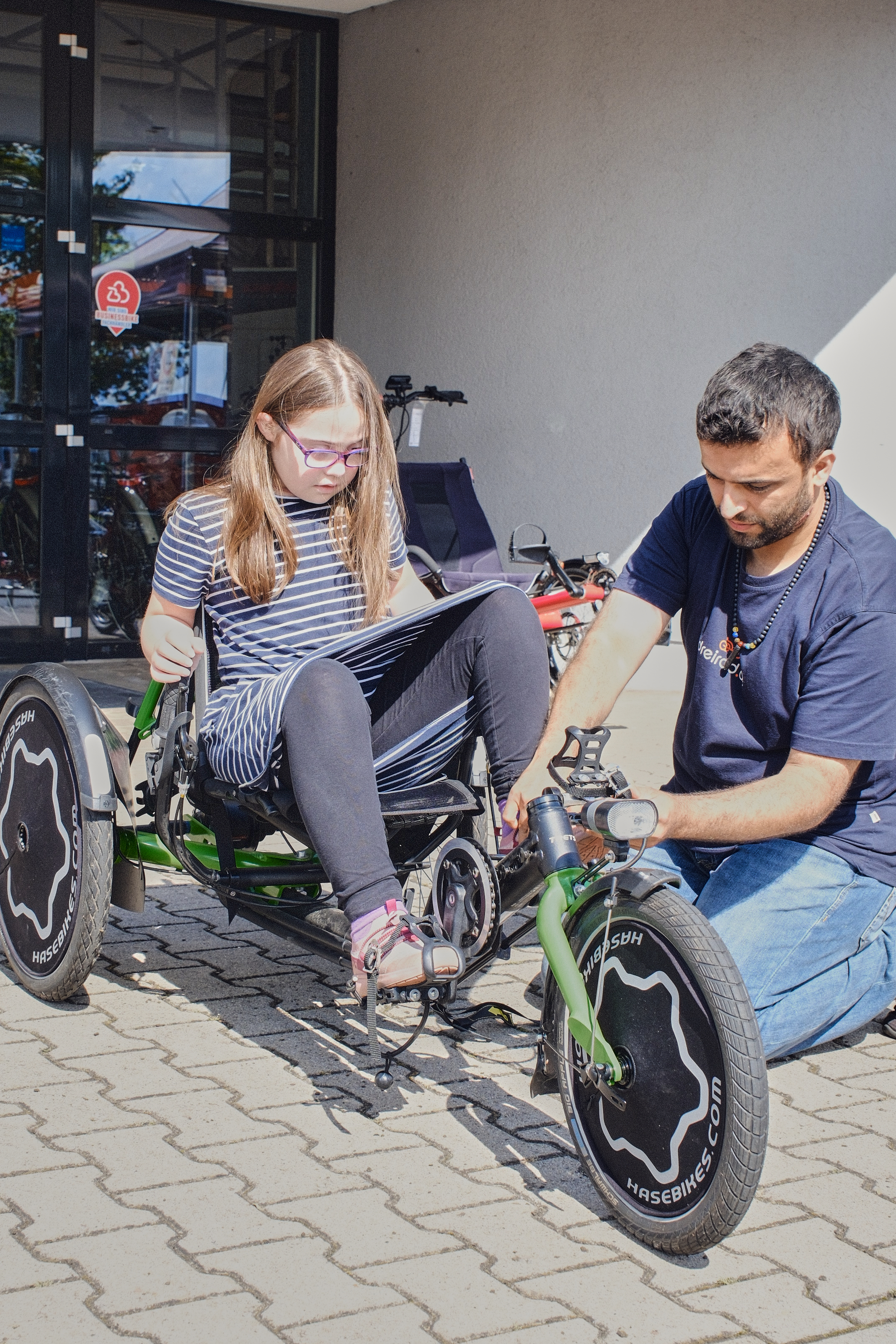 Kind sitzt auf Liegerad und Mann daneben