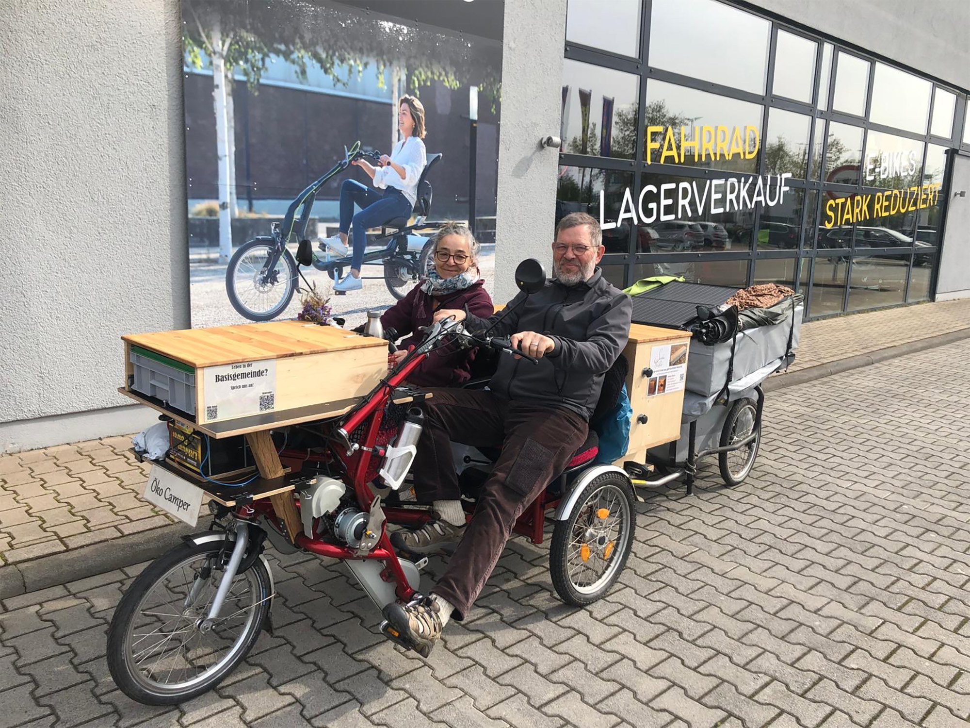 zwei personen auf voll beladenem dreirad 