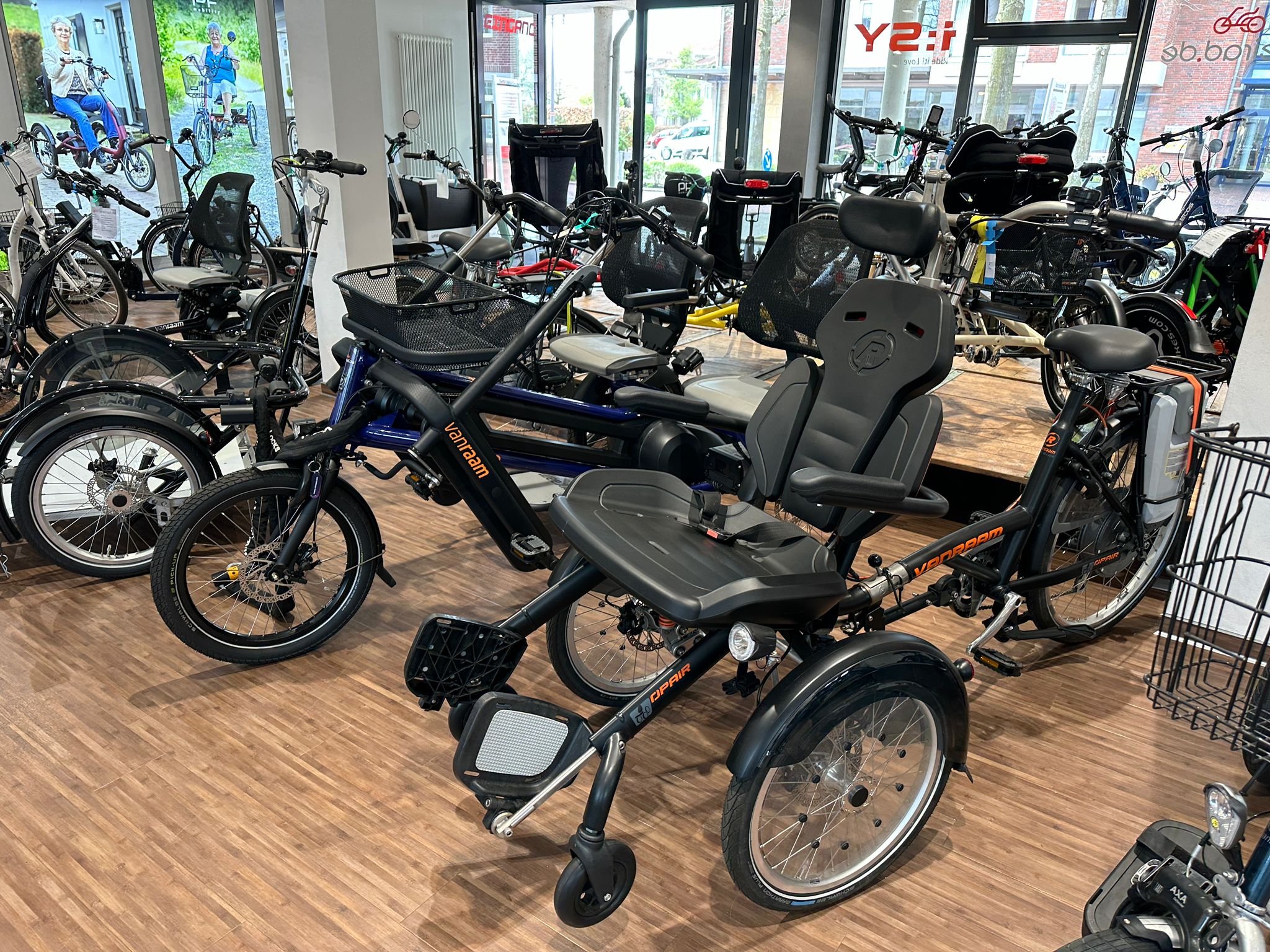 Van Raam Dreirad mit Komfortsitz im Ausstellungsraum, umgeben von Spezial- und E-Bikes.