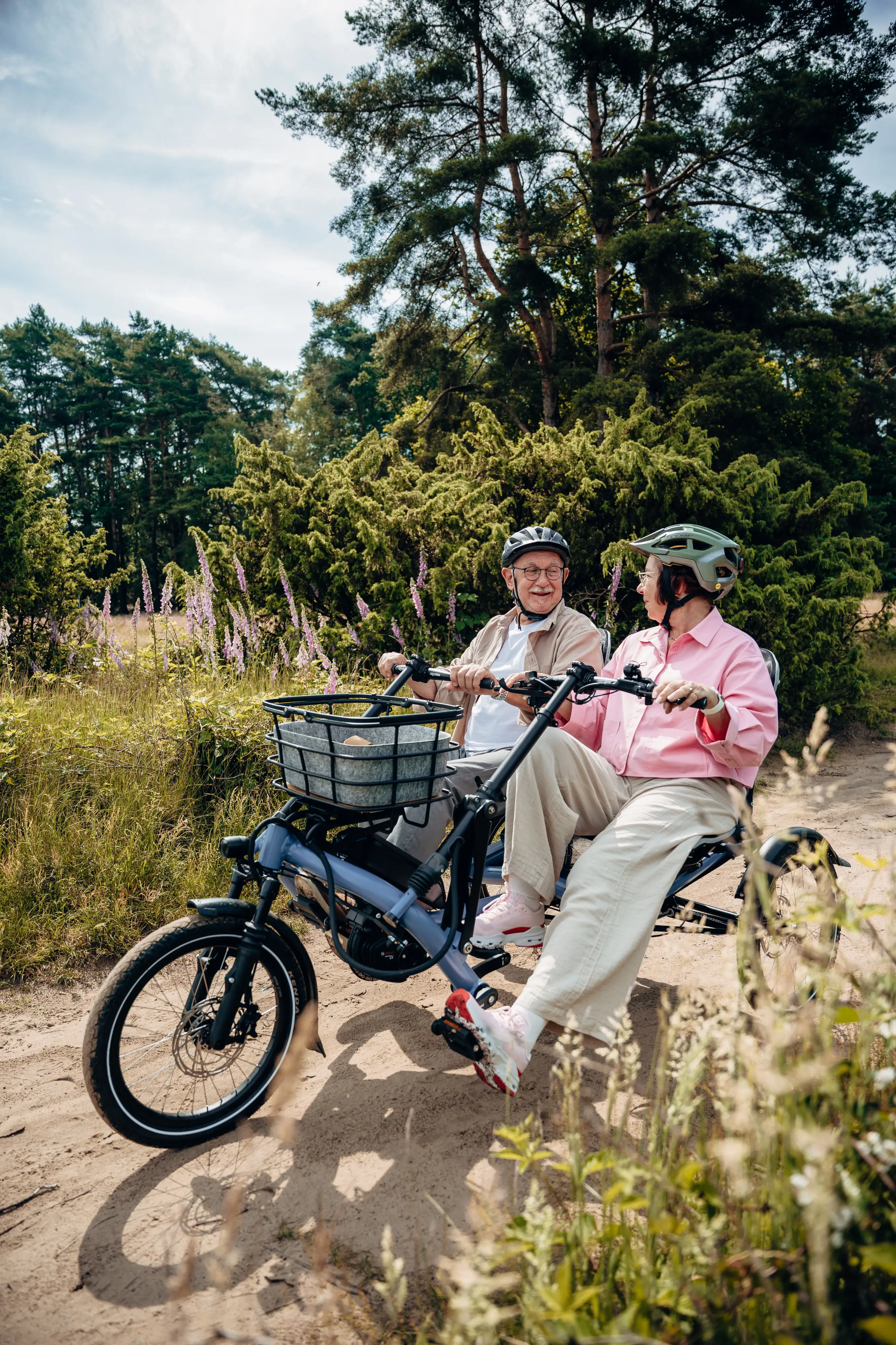 Eine Frau und ein Mann fahren Paralleltandem und lächeln sich an